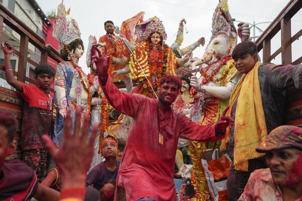 Devotos hindúes indios bailan durante el festival Durgá Puyá en Prayagraj, Uttar Pradesh, la India. La inmersión de los ídolos marca el fin del festival que conmemora la muerte de un rey demonio a manos de la diosa Durga, montada en un león y con 10 brazos, lo que supone el triunfo del bien sobre el mal. - Sputnik Mundo