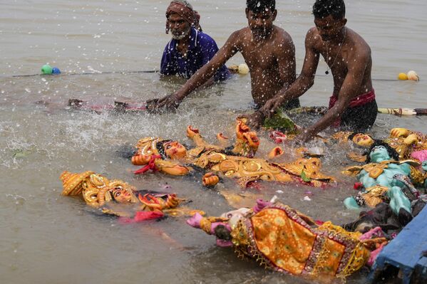 Trabajadores arrastran hacia aguas más profundas y rocían agua bendita sobre un ídolo de la diosa hindú Durga después de sumergirlo en el río Hugli, en Calcuta. - Sputnik Mundo