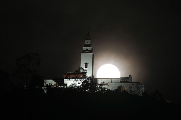 Las superlunas solo se producen unas pocas veces al año, ya que las posibilidades de su aparición en el cielo nocturno dependen de determinados factores.En la foto: la Superluna se cierne sobre una basílica en Bogotá, Colombia. - Sputnik Mundo