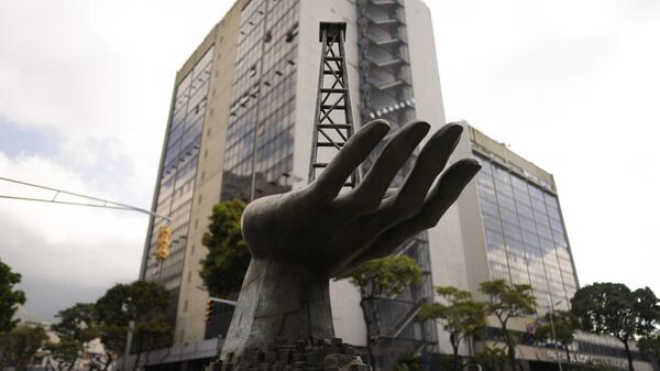 Una escultura de una mano sosteniendo un pozo de petróleo junto a la petrolera estatal Petróleos de Venezuela S.A. (PDVSA), detrás, en Caracas, Venezuela (archivo) - Sputnik Mundo