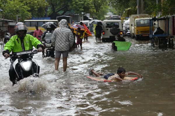 La gente vadea una calle inundada durante las fuertes lluvias en la ciudad india de Chennai. - Sputnik Mundo