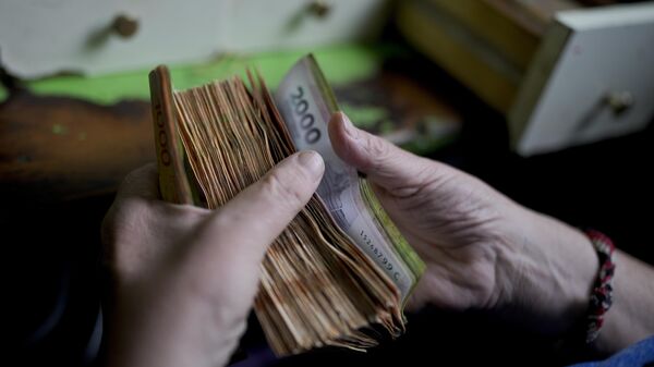 Un trabajador argentino cuenta dinero en una tienda en Buenos Aires, Argentina (imagen referencial) - Sputnik Mundo