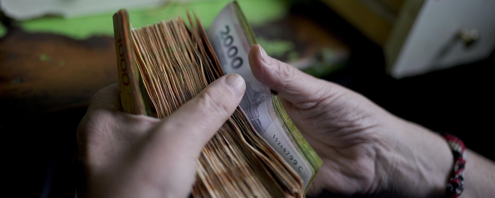 Un trabajador argentino cuenta dinero en una tienda en Buenos Aires, Argentina (imagen referencial) - Sputnik Mundo, 1920, 18.12.2024