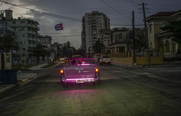 Un automóvil clásico estadounidense con una bandera cubana circula por una calle de La Habana durante el apagón. - Sputnik Mundo