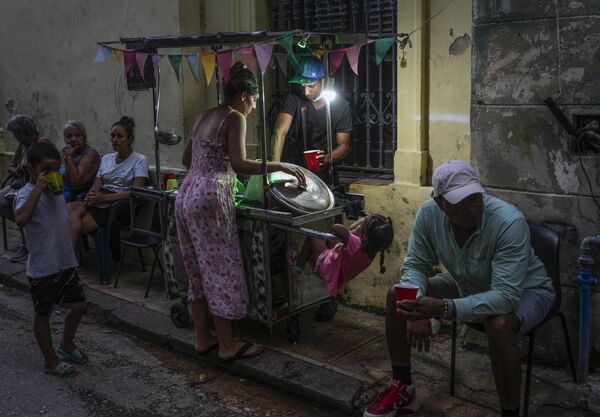 Una mujer comprándole sopa a un vendedor ambulante durante el apagón en La Habana. - Sputnik Mundo