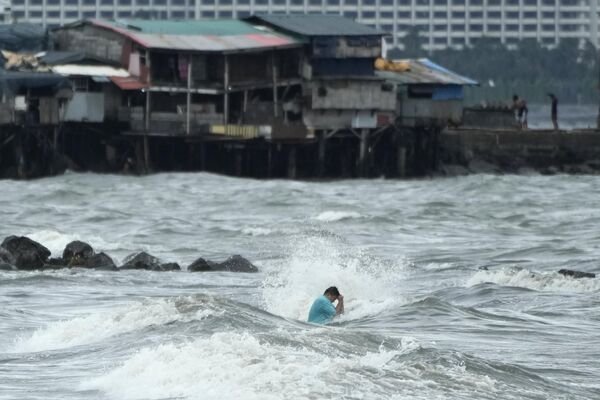 Un hombre resultó atrapado en una zona severamente inundada en medio de la tormenta tropical Trami en la capital filipina, Manila. - Sputnik Mundo