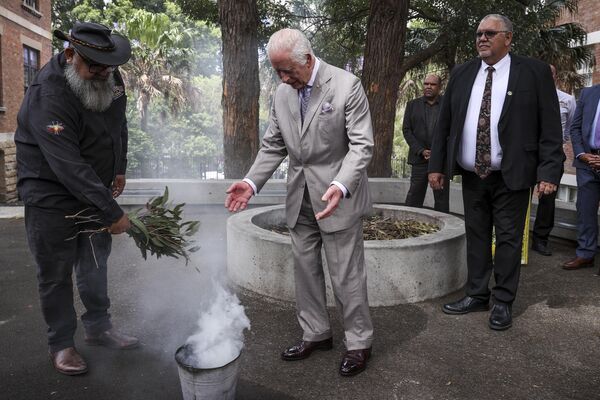 El rey británico Carlos III (en el centro) participando en una ceremonia tradicional de fumadores dirigida por representantes del grupo étnico Eora en Australia. - Sputnik Mundo