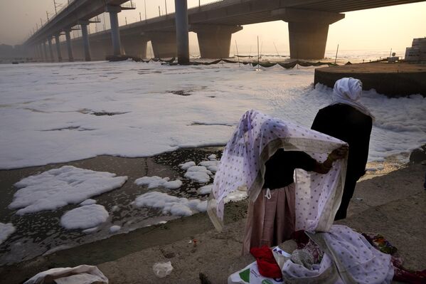 Una mujer se cambia de ropa tras rezar cerca del río Yamuna, contaminado con espuma tóxica, en la capital india de Nueva Deli. - Sputnik Mundo