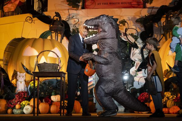 Truco o trato (trick-or-treat en inglés) es una actividad de las celebraciones de Halloween en la que los niños disfrazados recorren las casas de su vecindario, pidiendo dulces.En la imagen: el presidente estadounidense Joe Biden invita a los niños a un truco o trato en vísperas de Halloween frente a la Casa Blanca en Washington. - Sputnik Mundo