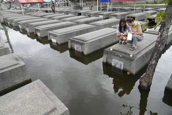 Un grupo de mujeres coloca velas sobre una tumba semisumergida de familiares en el Parque Memorial del Espíritu Santo en Masantol, Filipinas. - Sputnik Mundo