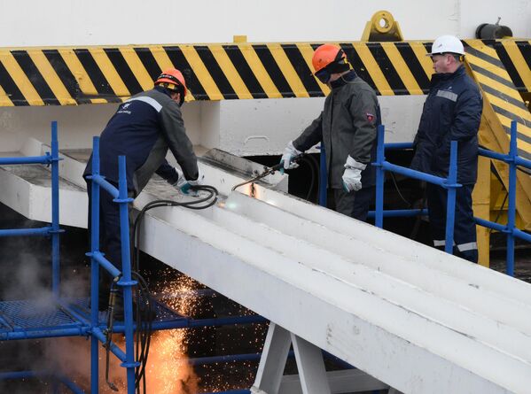 Trabajadores cortan la estructura metálica que mantenía anclado el buque en la ceremonia de botadura del rompehielos nuclear Chukotka (Proyecto 22220) en los Astilleros Bálticos de la USC en San Petersburgo. - Sputnik Mundo