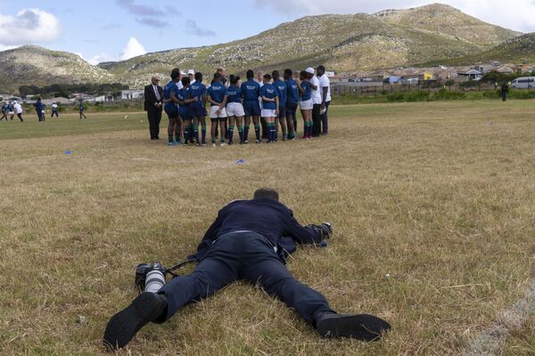 Un fotógrafo se tira al suelo para tomar una foto del príncipe Guillermo de Gales en su saludo a los alumnos del Ocean View High School de Ciudad del Cabo, Sudáfrica. - Sputnik Mundo