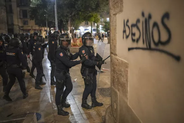 Policías antidisturbios pasan junto a una pintada en la que se puede leer "asesinos" durante los enfrentamientos. Policías antidisturbios pasan junto a una pintada en la que se puede leer "asesinos" durante los enfrentamientos. - Sputnik Mundo