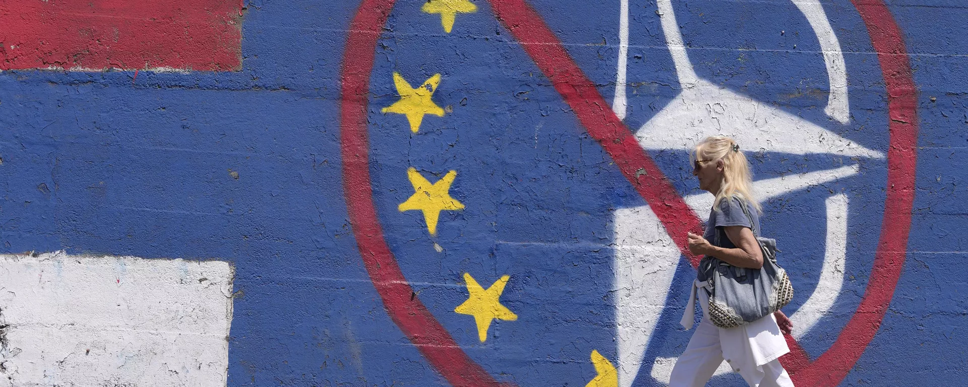 Una persona camina junto a un mural contra la UE y la OTAN en Belgrado el 30 de marzo de 2022 - Sputnik Mundo, 1920, 12.11.2024