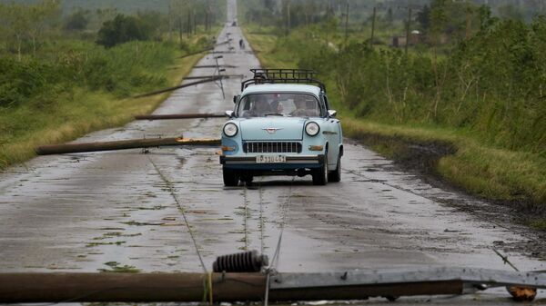 Un grupo de personas circula por una carretera llena de cables eléctricos caídos tras el paso del huracán Rafael en Cuba - Sputnik Mundo