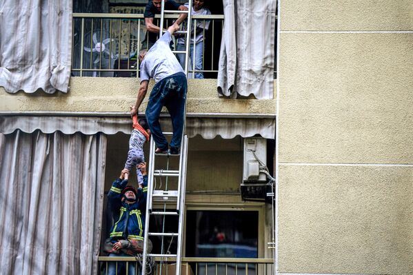 Agentes de la defensa civil libanesa rescatan a un niño de un edificio durante un incendio en Beirut, Líbano. - Sputnik Mundo