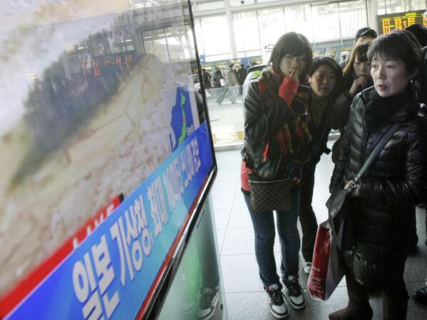Turistas japoneses ven un noticiario de televisión sobre un gran terremoto en su país en la estación de tren de Seúl, Corea del Sur, el 11 de marzo de 2011. En las letras se lee: &quot;La Agencia Meteorológica de Japón advierte de un tsunami&quot;. - Sputnik Mundo