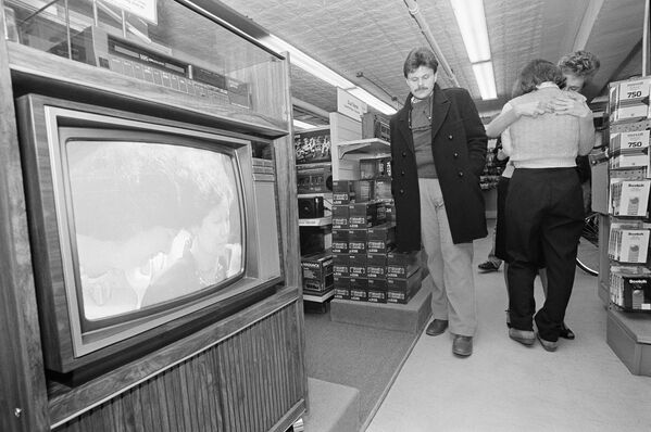 El comprador David Kimball reacciona mientras las empleadas de la tienda se abrazan durante un servicio conmemorativo en Houston por los astronautas fallecidos en la explosión del Challenger, EEUU. - Sputnik Mundo