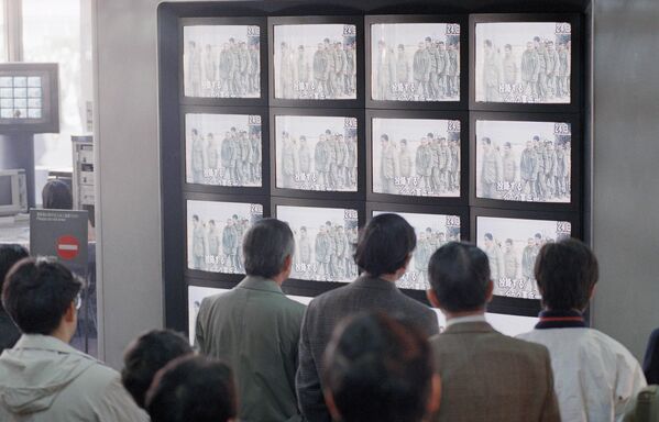 Un pequeño grupo de personas se detiene frente a un monitor multipantalla para ver las noticias del mediodía del martes, en las que se muestra la rendición de los soldados iraquíes a las fuerzas aliadas. - Sputnik Mundo