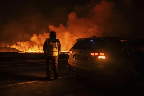 Debido al cataclismo natural, los residentes de la ciudad Grindavík, así como los visitantes y empleados del popular balneario geotérmico Blue Lagoon, fueron evacuados por el servicio de rescate.En la foto: un reportero observando la nueva erupción volcánica desde la carretera a Grindavík. - Sputnik Mundo