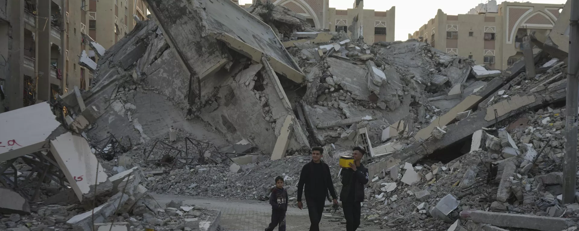 Jóvenes palestinos caminan entre los edificios destruidos por los bombardeos israelíes en un vecindario de Jan Yunis, al sur de la Franja de Gaza (imagen refrencial) - Sputnik Mundo, 1920, 18.12.2024