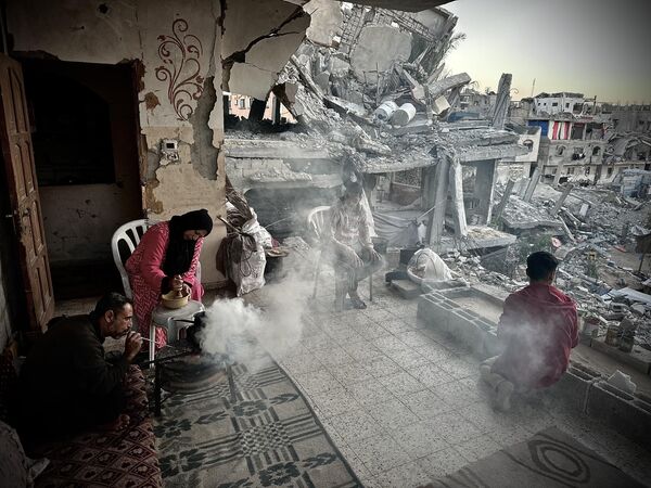 Una familia palestina desplazada, en un edificio dañado, se reúne en torno a una hoguera para calentarse en medio del frío y la crisis alimentaria en Jan Yunis, Franja de Gaza. - Sputnik Mundo
