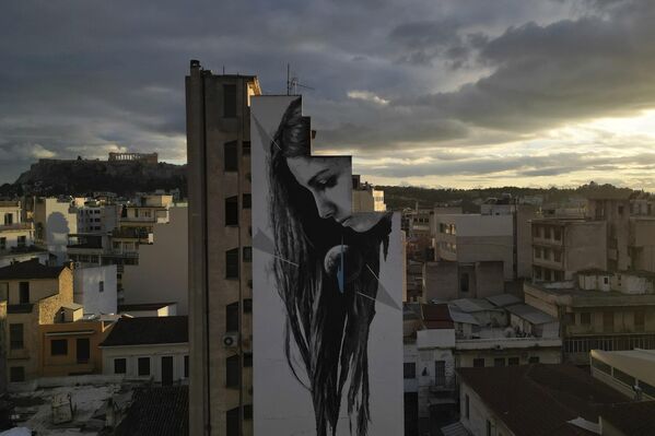 Una foto aérea tomada por un dron muestra My World (Mi mundo) una pintura acrílica del artista visual Ino, parte de una campaña medioambiental alternativa en espacios públicos a través del arte, cubriendo la pared de un edificio mientras se ve la antigua colina de la Acrópolis al fondo, en Atenas, Grecia. - Sputnik Mundo