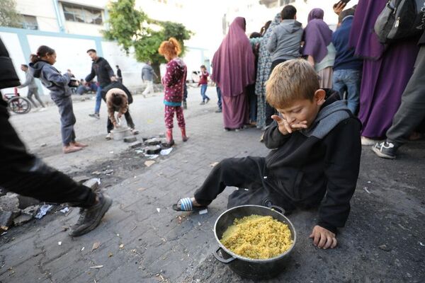 Palestinos de la Franja de Gaza hacen cola para recibir alimentos distribuidos por organizaciones caritativas. - Sputnik Mundo