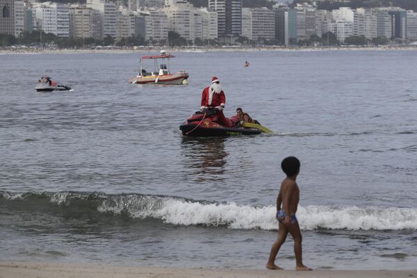 Un bombero disfrazado de Papá Noel rescata a una persona en la playa de Copacabana, en Río de Janeiro. - Sputnik Mundo