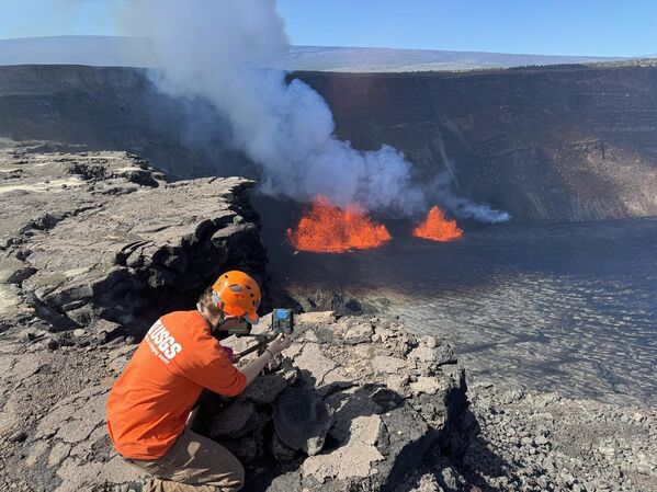 Un geólogo del Observatorio Volcánico Hawaiano del Sevicio Geológico de EEUU comprueba una webcam situada en el borde de la caldera del volcán Kilauea. La red de cámaras web en la cima es fundamental para monitorear las erupciones. - Sputnik Mundo