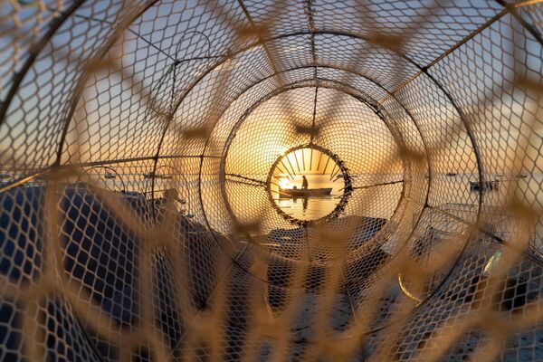 Un pescador regresa al puerto al amanecer en las Islas Querquenes, visto a través de una trampa para peces, Túnez. Un pescador regresa al puerto al amanecer en las Islas Querquenes, visto a través de una trampa para peces, Túnez. - Sputnik Mundo
