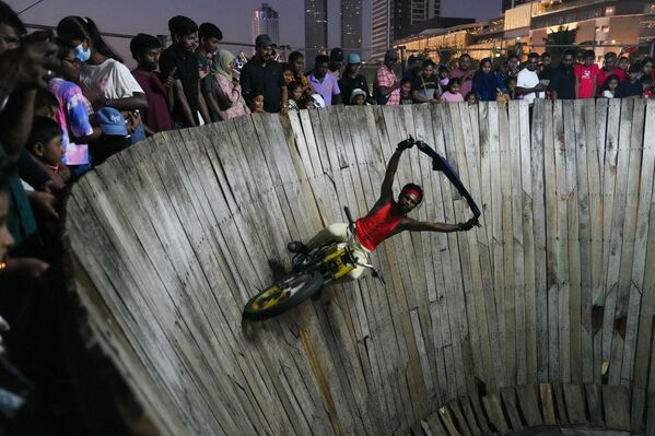 Durante un espectáculo en la Pared de la muerte, artistas montan motocicletas o automóviles dentro de un cilindro de madera, desafiando la gravedad gracias a la fuerza centrífuga.En la imagen: artistas de circo actúan en la Pared de la muerte en la capital ceilanesa, Colombo. - Sputnik Mundo