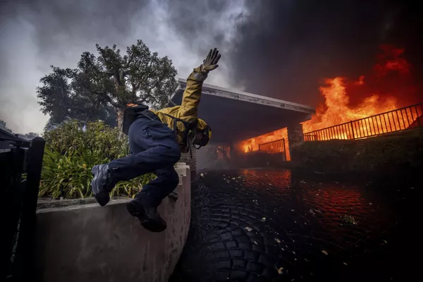 Un bombero salta una valla mientras lucha contra el incendio en Pacific Palisades en Los Ángeles, California. - Sputnik Mundo