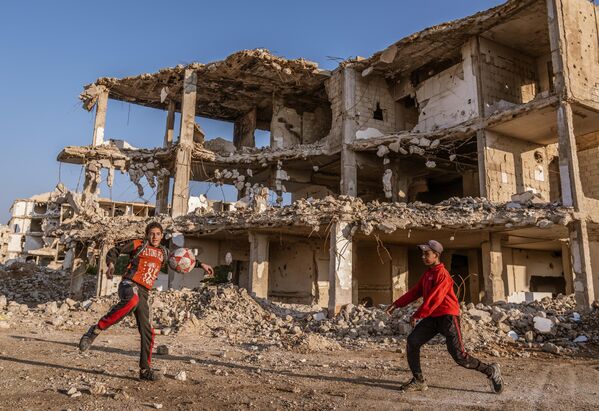 Unos menores juegan en la calle frente a los edificios dañados por el conflicto interno sirio, en la capital, Damasco. No hay un solo edificio en esta zona que no haya sido dañado por los intensos ataques. Unos menores juegan en la calle frente a los edificios dañados por el conflicto interno sirio, en la capital, Damasco. No hay un solo edificio en esta zona que no haya sido dañado por los intensos ataques. - Sputnik Mundo
