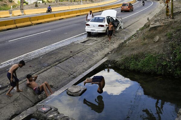 Un niño se lanza de cabeza a una zanja de drenaje en Caracas, Venezuela. Un niño se lanza de cabeza a una zanja de drenaje en Caracas, Venezuela. - Sputnik Mundo