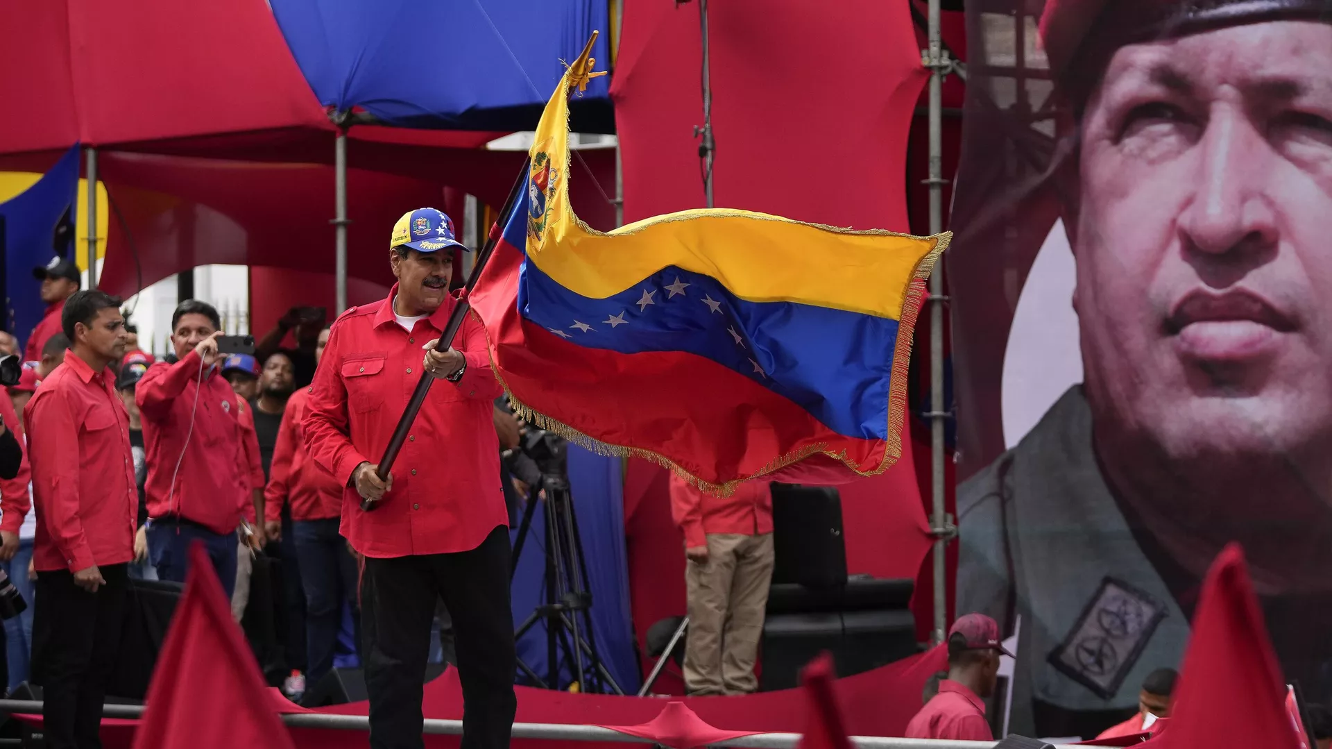 El presidente Nicolás Maduro ondea una bandera de Venezuela adelante del retrato de Hugo Chávez - Sputnik Mundo, 1920, 19.01.2025