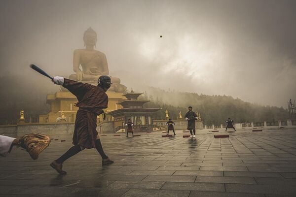 En 2024 había cuatro premios en la categoría foto única (One Shot, en inglés), que retaban a los fotógrafos a capturar el tema de cada categoría en una sola imagen.Así, el ganador de Foto única: ciudades, pueblos, calles fue estadounidense Matthew DeSantis con su brumosa imagen de un partido de béisbol frente a un Buda gigante en Bután. - Sputnik Mundo
