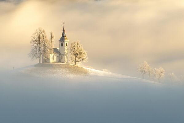 La serena imagen del fotógrafo de Hong Kong, Ngar Shun Victor Wong, de un paisaje y una iglesia cubiertos de nieve es hermosa por sí misma, pero lo es aún más cuando se ve la diminuta figura humana que le da el contexto.Así, la obra se convirtió en la ganadora de foto única: Escapada. - Sputnik Mundo