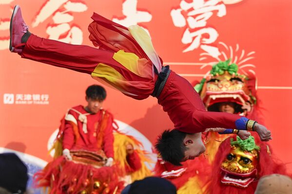 En China son especialmente comunes las procesiones tradicionales con enormes dragones y leones increíblemente coloridos.El león es un personaje poderoso y majestuoso en la mitología china.En la foto: un artista da saltos mortales junto a bailarines leones en la Feria del Templo del Parque Longtan en Pekín. - Sputnik Mundo