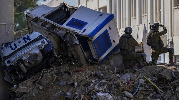 Soldados israelíes toman posición junto a vehículos de la ONU arrugados y precariamente encaramados sobre escombros en el complejo de la UNRWA, el jueves 8 de febrero de 2024 - Sputnik Mundo
