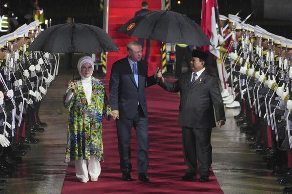 El presidente indonesio Prabowo Subianto acoge con un paraguas al presidente turco Recep Tayyip Erdogan y a su esposa Emine tras su llegada al aeropuerto de la capital indonesia, Yakarta. - Sputnik Mundo