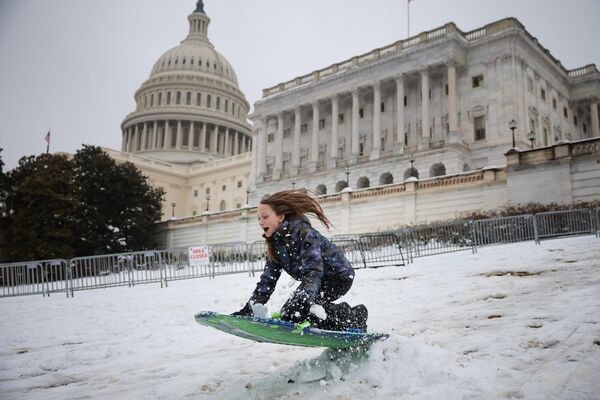 Una niña deslizándose en trineo por una rampa frente al Capitolio, en la capital de Estados Unidos, Washington D. C. - Sputnik Mundo