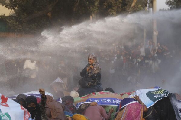 La Policía carga con porras y utiliza cañones de agua, gas lacrimógeno y granadas aturdidoras para dispersar a los manifestantes que exigen la restitución de los nombramientos de profesores auxiliares en las escuelas primarias públicas de Daca, Bangladés. - Sputnik Mundo