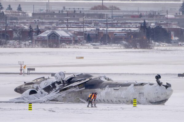 Trabajadores del aeropuerto internacional Pearson de Toronto, Canadá, inspeccionan el lugar del accidente de un avión de Delta Air Lines en el que resultaron heridos al menos 18 pasajeros. - Sputnik Mundo