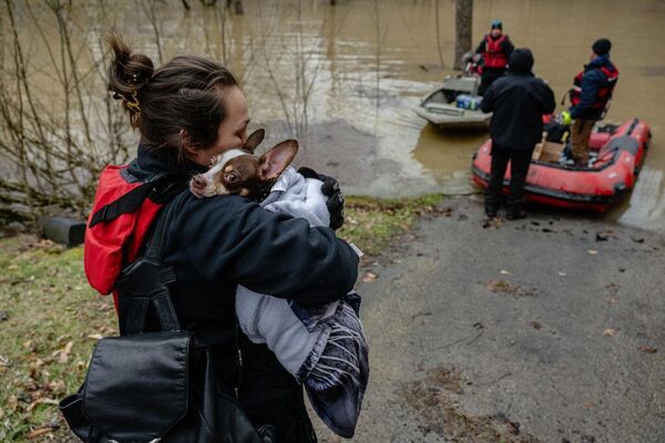 Una mujer sostiene a su perro mientras evacuan a ambos durante una operación de rescate lanzada en una zona fuertemente inundada en el condado de Leslie, EEUU. - Sputnik Mundo