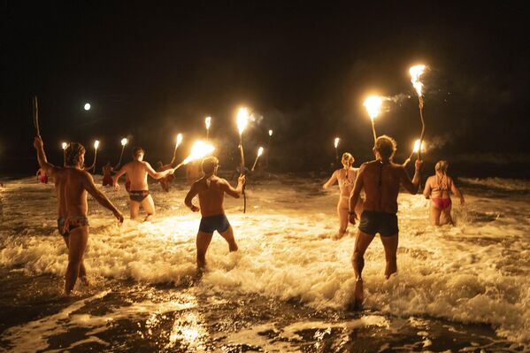 Los socorristas con antorchas se adentran en el océano Atlántico en una ceremonia con motivo del Día del Guardavidas, para honrar su compromiso con la seguridad y el rescate en el agua, Argentina. - Sputnik Mundo