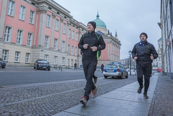 El canciller alemán saliente Olaf Scholz haciendo jogging acompañado de su guardaespaldas. - Sputnik Mundo