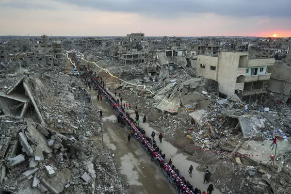 Mientras el sol se pone, los palestinos se reúnen para el iftar, la comida de ruptura del ayuno en el primer día de Ramadán, en una gran mesa rodeada por los escombros de casas y edificios destruidos en Rafah, al sur de la Franja de Gaza. - Sputnik Mundo