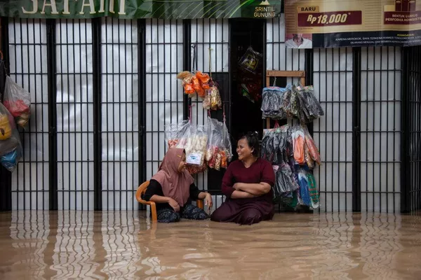 Unas vendedoras se sientan en una calle inundada, frente a sus tiendas, tras colgar sus bienes en lo alto para evitar que se mojen, en la ciudad de Bekasi, Indonesia. - Sputnik Mundo