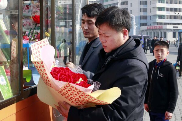 Ciudadanos de Pionyang, Corea del Norte, compran ramos de flores en un quiosco con artículos de temática floral. - Sputnik Mundo